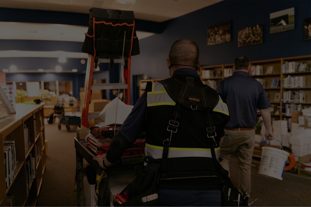 service technician pushing a ladder through library