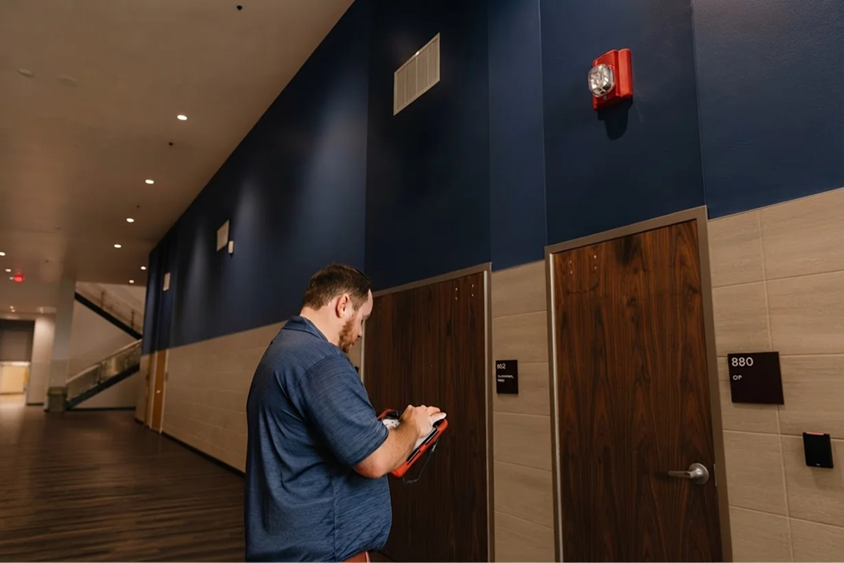 worker performing safety inspection on fire alarm